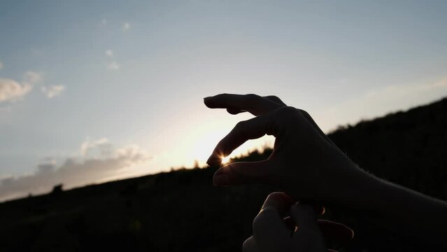Female fingers hold the sun at sunset