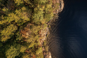 Top down view of tree-covered rocky island on Lake Ladoga illuminated by rising sun, Karelia, Russia
