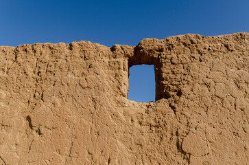 Ruin stone wall with window against blue sky
