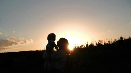 Silhouette of a mother with a child at sunset in the mountains