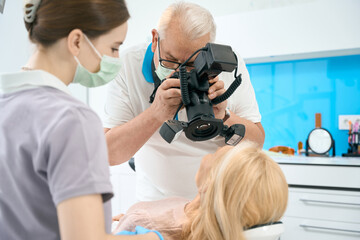 Stomatologist making photo of teeth using camera with flash