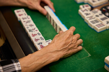 Elderly people playing mahjong, indoor gamble activity at home during spring festival.