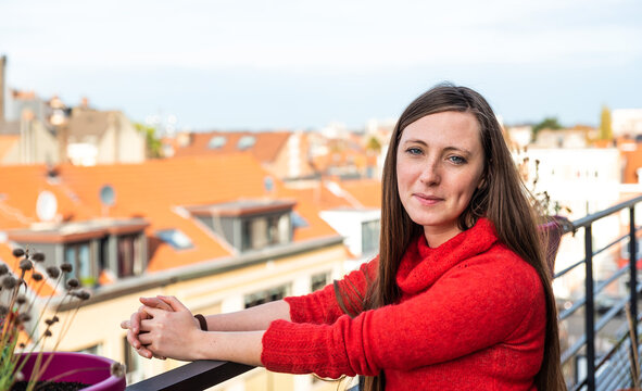 Portrait Of An Attractive Thirty Year Old White Woman In Red Posing On A Terrace