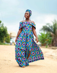 candid image of beautiful african lady walking outside- black woman dressed in african print