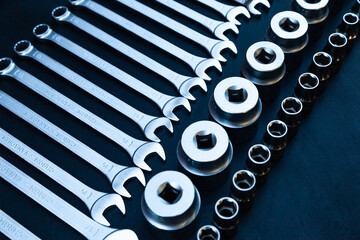 A set of wrenches and hex sockets on a black background.