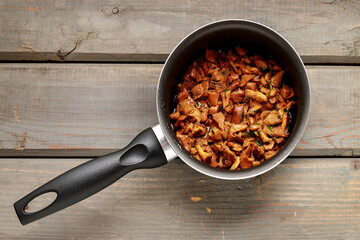 Cantharellus cibarius, commonly known as the chanterelle, golden chanterelle or girolle. Mushrooms with butter in a big pot.