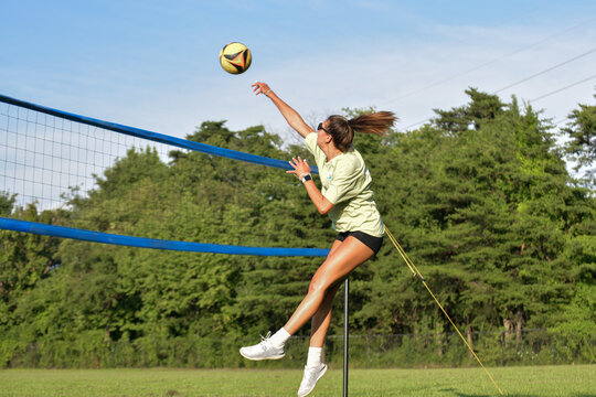 Female volleyball player hitting the ball on a grass doubles game