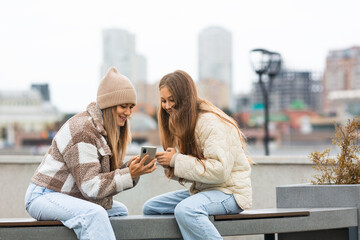 Trust and understanding between generations - mom and daughter spending free time together, using smart phones looking at the screen of a smartphones sharing photo, showing content.