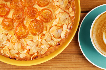 Closeup homemade pie with apricots and cup of coffee cappuccino on wooden table. Top view.