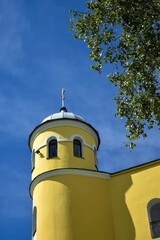 View from below of church tower with arched windows and metal dome with cross against cloudy sky. Theme of religion and church architecture. Copy space. Selective focus.