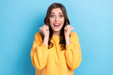 Photo portrait of gorgeous young lady raise fists win lottery cute reaction dressed stylish yellow look isolated on blue color background