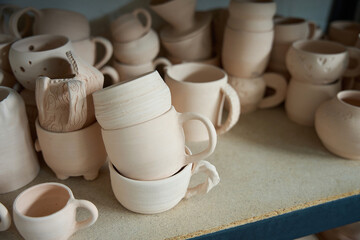 Fototapeta na wymiar Raw clay cups stand on a shelf