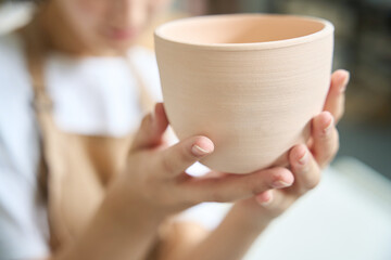 Close-up of a large clay cup in female hands