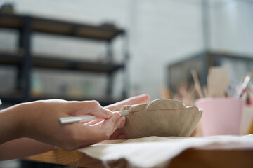 Obraz premium Craftswoman holds a stack and clay blank in her hands