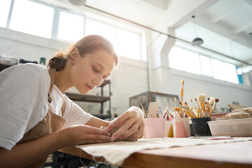 Obraz premium Young craftswoman works intently with a piece of clay