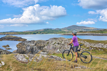 Fototapeta premium nice senior woman on mountain bike, cycling on the cliffs of Toormore,County Cork in southwestern Ireland