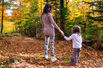 Happy mother and daughter walking along a trail in foliage season