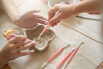 Craftswomen apply a pattern to a clay plate