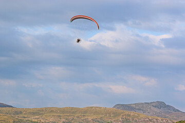 Fototapeta na wymiar Paramotor pilot flying in the hills of Wales 