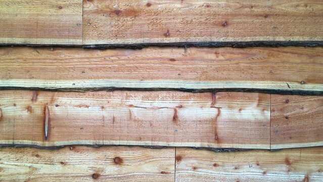 Close up of rustic waney edge wooden boards shed facade. 4k high quality video.
