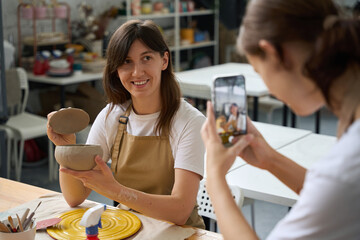 Woman holds clay pot in her hands, she is filmed student