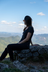 Young woman seated and looking to the horizon from the ruines of the Montsegur castle in France