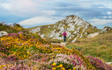 nice senior woman on mountain bike, cycling in sunset on the cliffs of Sheeps Head, County Cork, in...