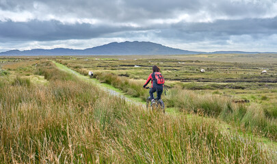 nice senior woman on mountain bike, cycling in the bog Area near Derrycunlagh, County Galway, in  the western part of the Republic of Ireland
