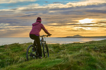 nice senior woman on mountain bike, cycling in sunset in the sand dunes of Sillerna, Grallagh,...
