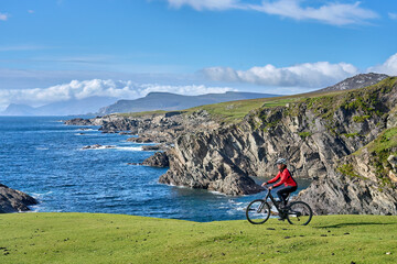 nice senior woman on mountain bike, cycling on the cliffs of Achill Island, Carrowgarve, Republik...