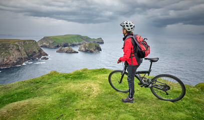 Naklejka premium nice senior woman on mountain bike, cycling on the cliffs of Cnoc an Daimh, Kilgalligan the northern part of thr Republic of Ireland 