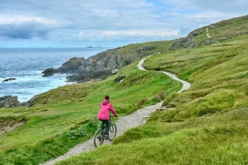 Fototapeta premium nice senior woman on mountain bike, cycling on the cliffs of Malin Head, the northern most point of Ireland