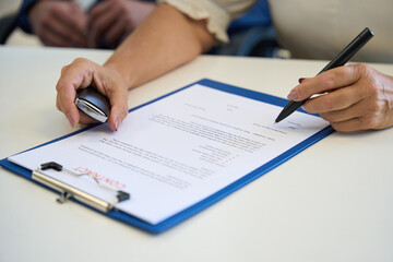 Car dealership female signing documents at the office desk