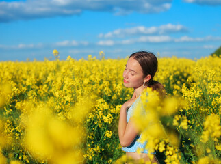 Fototapeta premium Beautiful teen girl is smiling with yellow flowers in summer field