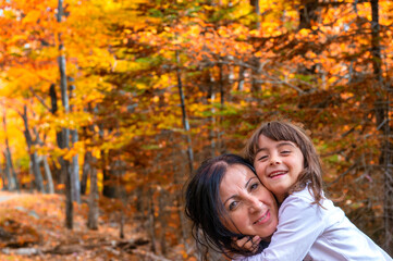 Fototapeta premium Happy mother and daughter walking along a trail in foliage season