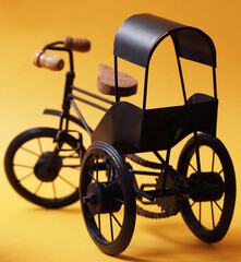 Fototapeta na wymiar Decorative souvenir bike. Vintage tricycle cart on a yellow background. Shallow depth of field
