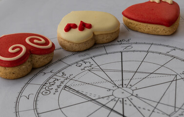 Printed astrology chart with Venus and Saturn  planets; red and yellow heart shaped cookies in the...