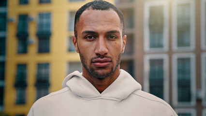 American latino man handsome male athletic muscular guy serious looking at camera stand on city...