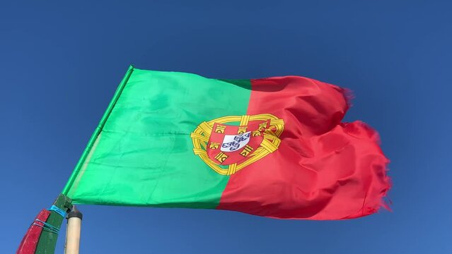 Waving flag of Portugal in windy weather with blue sky in the background.