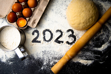 Baking flour and number 2023 on blackboard. Top view. New year ornament food background. Home made.