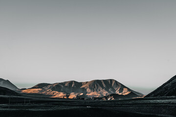 sad landscape of desert and lonely mountains under a gray sky without nature a car on the road at...