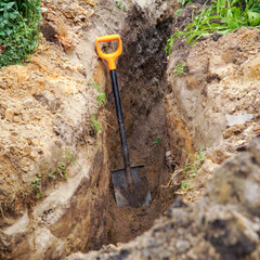 Fototapeta premium Shovel in the trench. The concept of earthworks.