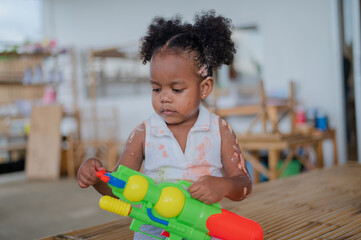 Portrait of Little afro girl smiling and playing colorful wooden toys at kindergarten.