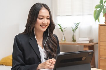 Online communication, asian young woman in formal suit wearing earphones, using tablet having online virtual job interview meeting conversation on video call, distance remote recruitment conference.