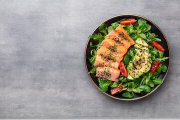 Salmon fish fillet with fresh salad, avocado top view.