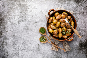 Pan filled with roasted potatoes shot on rustic wooden table.