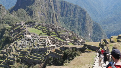 La ville de l'Inca Machu Picchu au sommet d'une montagne, avec les hautes montagnes voisines, son environnement vertigineux, ses murs de pierre bien polis, son jardin naturel et sa construction  - obrazy, fototapety, plakaty