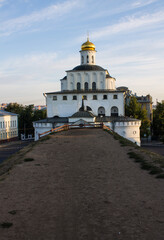 VLADIMIR, Russia - AUGUST, 18, 2022: white stone golden gate with a shiny dome in the old town on a sunny summer day against a blue sky