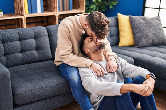 Young couple hugging each other and kissing sitting on sofa at home