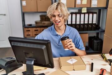 Young blond man ecommerce business worker drinking coffee using computer at office